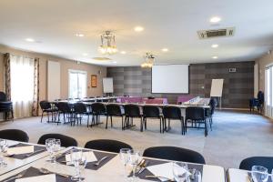 a conference room with tables and chairs and a projection screen at Kyriad Auxerre Appoigny in Appoigny