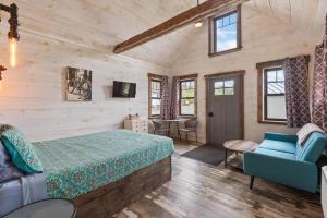 a bedroom with a bed and a couch and a tv at The Evergreen | Walk to Rangeley Lake, Sled & ATV Access in Rangeley