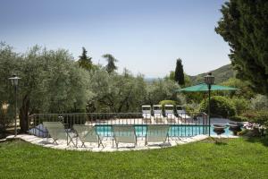 a pool with a group of chairs and an umbrella at Villa Terrarossa with Pool in the Vineyard in Mezzane di Sotto