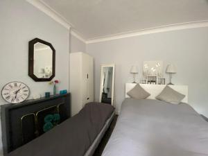 a bedroom with two beds and a clock on the wall at Spacious Double Studio-style room in Orpington