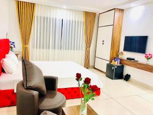 a bedroom with a bed and a chair and a television at Khách sạn Ruby - Gần trung tâm khảo thí in Cầu The