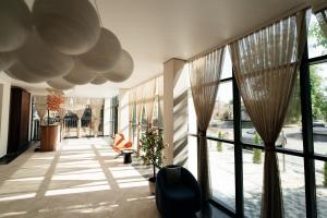 a hallway with large glass windows and a chair at Inzhu Premium Hotel in Taraz