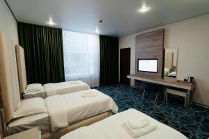 a hotel room with two beds and a television at Inzhu Premium Hotel in Taraz