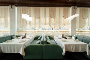 a dining room with two tables and green chairs at Inzhu Premium Hotel in Taraz