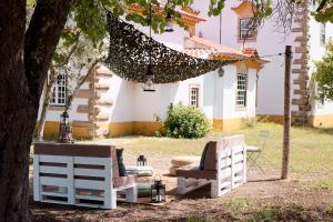 two chairs and a hammock in front of a house at Quinta Dos Ribeiros in Alpalhão