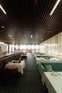 a restaurant with tables and couches and chairs at Inzhu Premium Hotel in Taraz