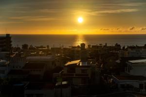 a sunset over a city with the ocean at Hotel Sunset ZANPA in Yomitan