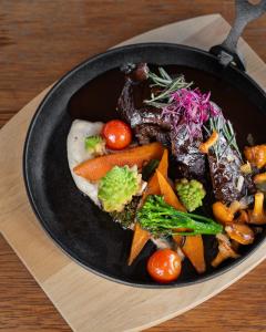 a pan filled with vegetables on a wooden table at Viinistu Art Hotel in Viinistu