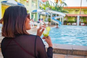 a woman holding a lime in front of a swimming pool at Hotel Parque das Aguas in Aracaju
