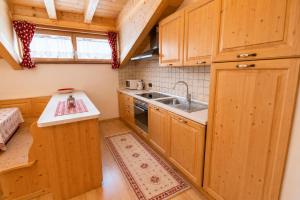 a kitchen with wooden cabinets and a sink at Rossetti Big by AMA Val di Fassa in Pozza di Fassa