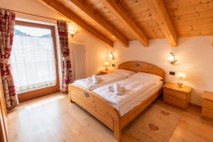 a bedroom with a bed in a room with a large window at Rossetti Big by AMA Val di Fassa in Pozza di Fassa