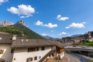 a view of a town with a bridge and mountains at Rossetti Big by AMA Val di Fassa in Pozza di Fassa