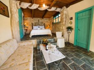 a bedroom with a bed and a couch and a table at Revera Traditional Stone Villas, Apartments & Studios in Keri