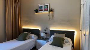two beds in a bedroom with two lamps on them at Hotel Restaurant Europeu in Montmeló