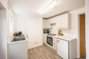 a kitchen with white cabinets and a sink at 10 Northgate, Beccles in Beccles