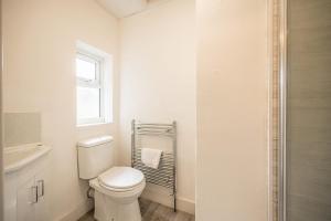 a white bathroom with a toilet and a window at 10 Northgate, Beccles in Beccles +15 photos