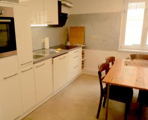 a kitchen with white cabinets and a wooden table at Schönste Aussicht in Königstein an der Elbe