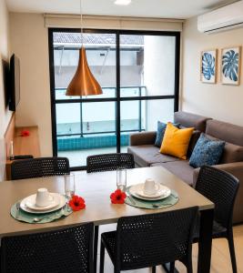 a living room with a table and chairs at Apartamento com Piscina Rooftop e Hidro perto do Centro e da Praia, Porto Blue Porto de Galinhas in Porto De Galinhas