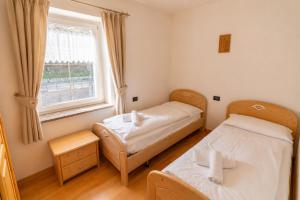 two beds in a room with a window at Rossetti 3 camere by AMA Val di Fassa in Pozza di Fassa