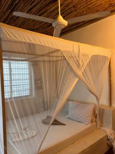a bed in a room with a mosquito net at Mambo Leo Hostel in Paje