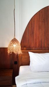 a bed with a wooden head board and a chandelier at Heritage Stay in Bingin Beach +10 photos