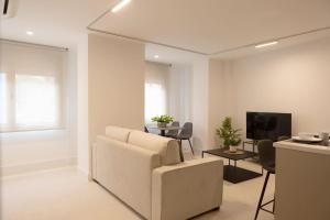 a living room with a white couch and a tv at Royar Apartamentos in Jaén