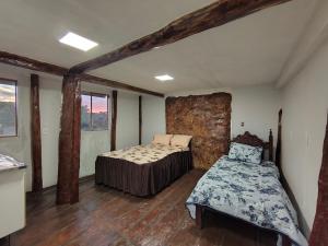 a bedroom with two beds in a room with wooden floors at Alpes Goianos - Suítes in Cavalcante