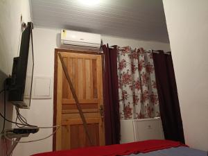 a bedroom with a bed and a television on top of a wooden door at Pousada Caranguejo in Cairu