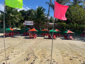 a beach with tables and chairs and umbrellas at Pousada Caranguejo in Cairu +1 photo