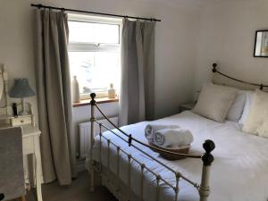 a bedroom with a white bed with a window at Berkley Cottage in Colchester