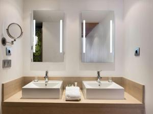 a bathroom with two sinks and two mirrors at NH Ciudad Real in Ciudad Real