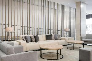 a living room with a white couch and two tables at NH Ciudad Real in Ciudad Real