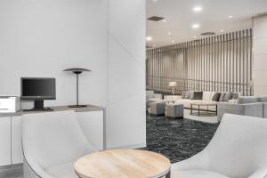 a living room with white chairs and a tv at NH Ciudad Real in Ciudad Real +28 photos
