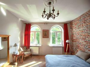 a bedroom with a bed and two windows with red curtains at Kamienica u Artystów in Sopot