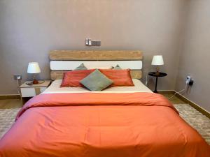 a bedroom with a large bed with orange sheets and pillows at Leaves & Stones in Kwedonu