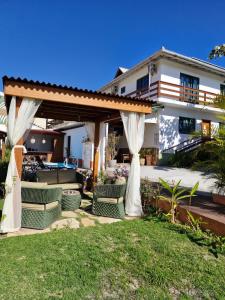 a backyard with a pergola and chairs and a house at Pousada Makani Kai in Florianópolis