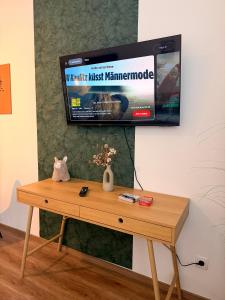 a tv hanging on a wall with a wooden table at Apartments Chloe - Top 3 in Hollabrunn +9 photos