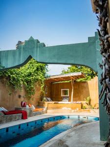a swimming pool in a backyard with a large green umbrella at Old Stone Boutique Lodge in Bagamoyo