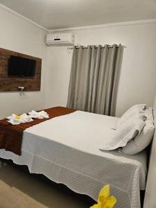 a bedroom with a large bed with a television on the wall at Casa de Charles in Piranhas +2 photos