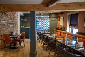 a restaurant with tables and chairs and a brick wall at The Crown & Thistle, Abingdon, Oxfordshire - Acorn Pubs in Abingdon