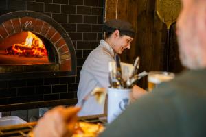 a chef preparing food in front of a brick oven at The Crown & Thistle, Abingdon, Oxfordshire - Acorn Pubs in Abingdon