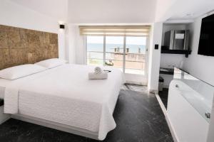 a white bedroom with a large bed and a window at Terramar Hoteles in Crucita +53 photos