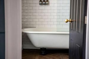 a white bath tub in a bathroom with white tiles at The Crown & Thistle, Abingdon, Oxfordshire - Acorn Pubs in Abingdon +65 photos