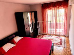 a bedroom with a red bed and a large window at Kiwi house in Podgorica
