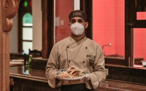 a chef wearing a mask holding a plate of food at Storii by ITC Hotels Shanti Morada Saligao, Goa in Calangute +114 photos