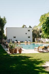 a swimming pool with picnic tables and benches next to a building at Masseria Montelauro in Otranto