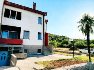 a building with a palm tree and a basketball hoop at Kiwi house in Podgorica