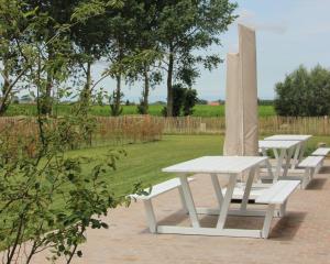 a row of white picnic tables in a park at Het Plategoed in Oosthoek