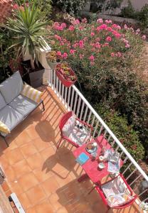 eine Terrasse mit Tisch, Stühlen und Blumen in der Unterkunft Solacargese-Le Jardin d'Irène-Vue panoramique exceptionnelle sur la Méditerranée in Cargèse