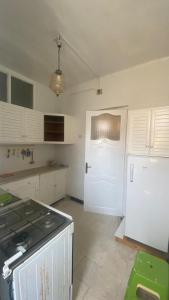a kitchen with a white refrigerator and a white door at Nice house ideally located in Dar Tahar Zaouch +6 photos